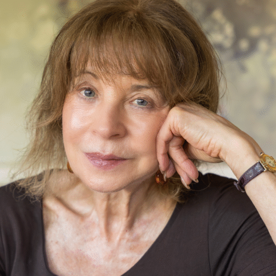 Jacqueline Rose sits looking at the camera, visible from the shoulders up and resting her head in one hand.