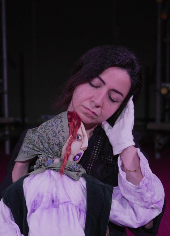 woman with long dark hair holding a hand puppet of a woman